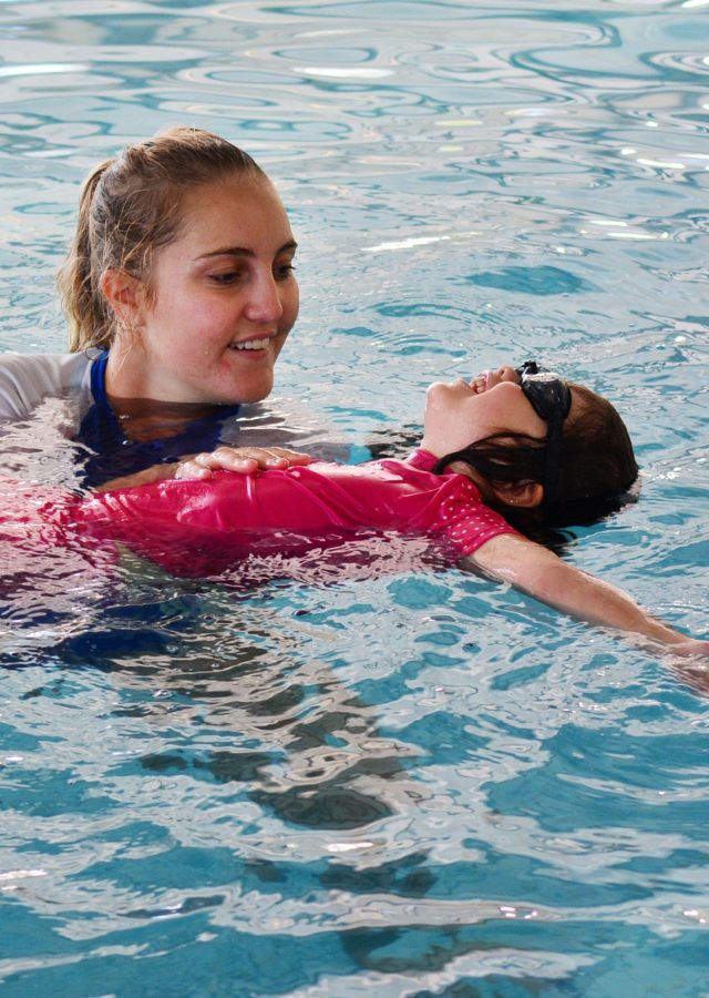 Swim instructor helps an infant feel comfortable in the water